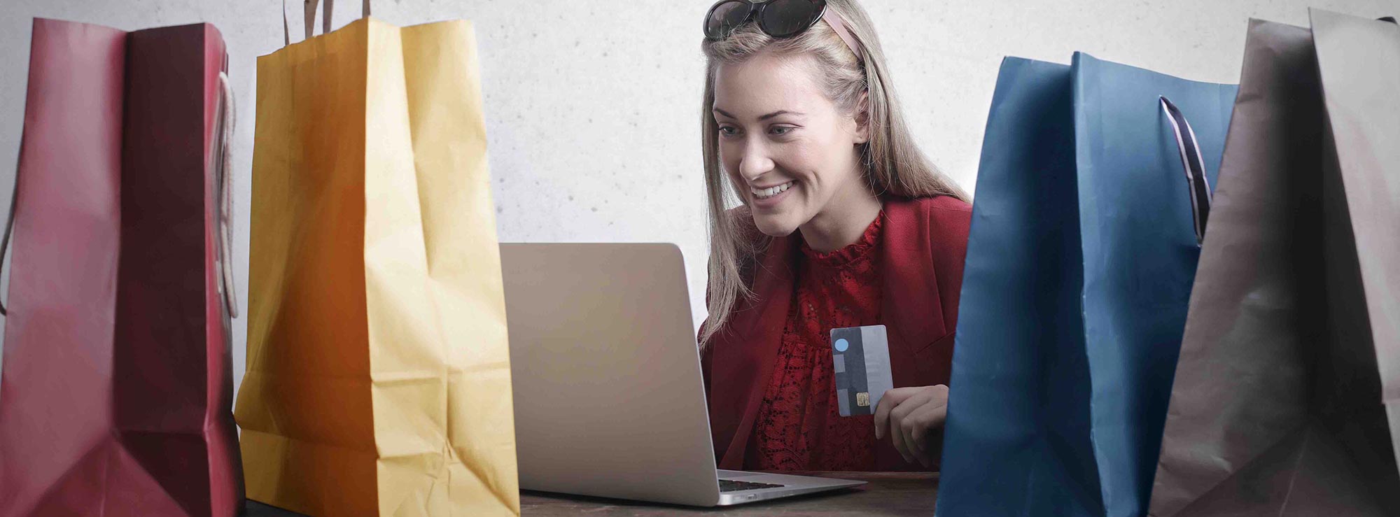 Femme souriante regardant son ordinateur entourée de plusieurs sacs